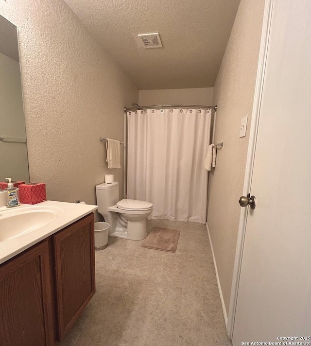 bathroom with vanity, toilet, curtained shower, and a textured ceiling