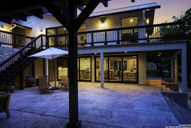 back house at dusk featuring a patio area