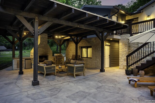 patio terrace at dusk featuring area for grilling and an outdoor living space with a fireplace