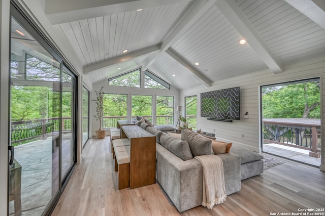 living room featuring vaulted ceiling with beams, plenty of natural light, and light wood-type flooring