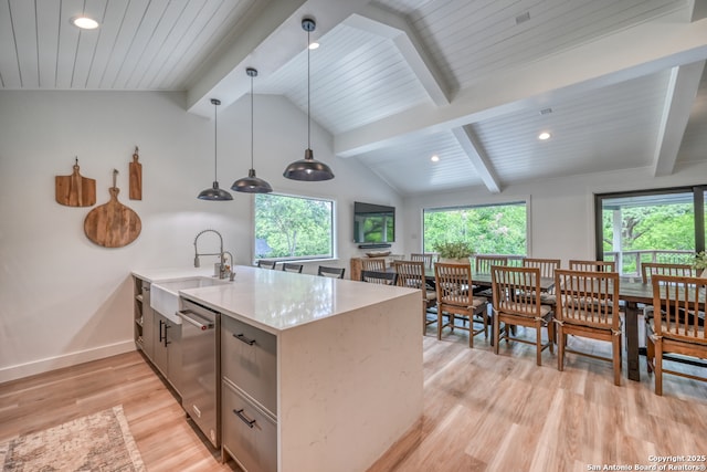 kitchen featuring light wood-type flooring, stainless steel dishwasher, kitchen peninsula, pendant lighting, and a healthy amount of sunlight