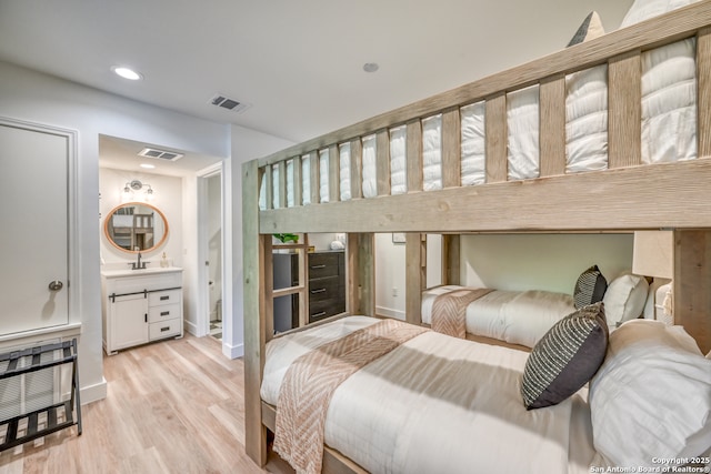 bedroom featuring heating unit, sink, and light hardwood / wood-style flooring