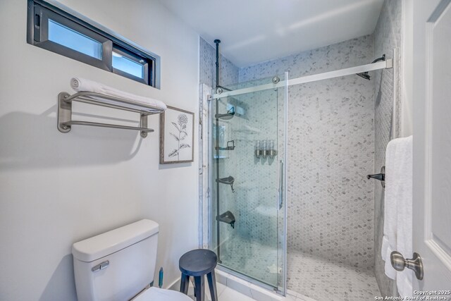 bathroom featuring a shower with door and toilet