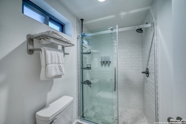 bathroom featuring toilet and a shower with shower door