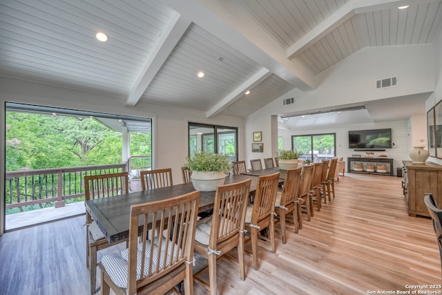 dining space featuring high vaulted ceiling, beam ceiling, and light hardwood / wood-style floors