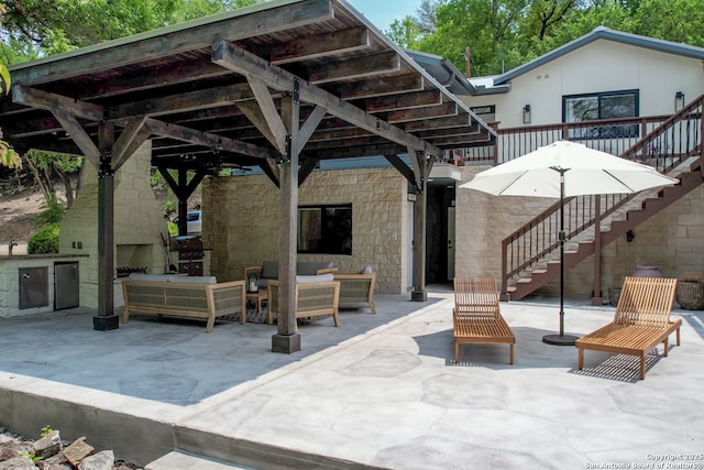 view of patio with exterior kitchen and an outdoor living space with a fireplace