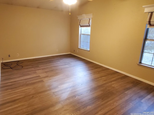 empty room featuring ceiling fan, plenty of natural light, and dark hardwood / wood-style floors