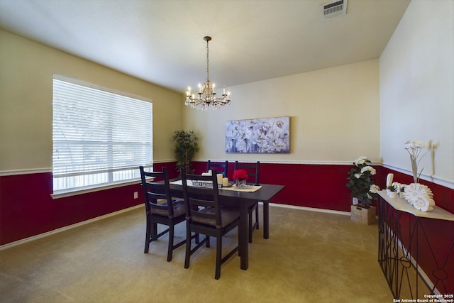 carpeted dining space with plenty of natural light and an inviting chandelier