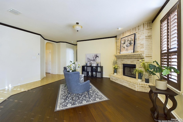 living room with ornamental molding, a wealth of natural light, hardwood / wood-style floors, and a fireplace