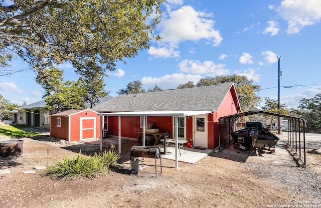 back of house with a carport and a shed