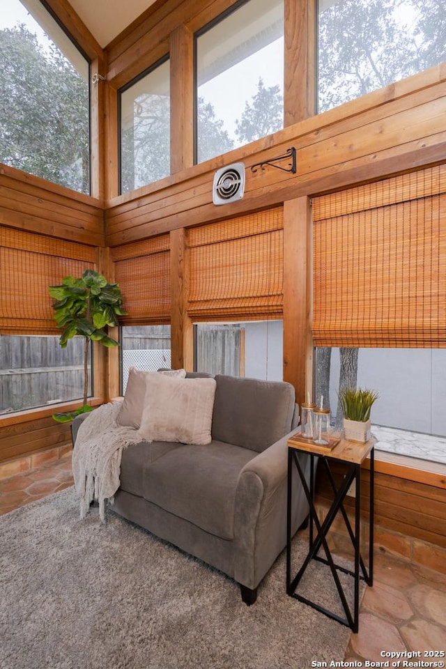 living room featuring a towering ceiling and wooden walls