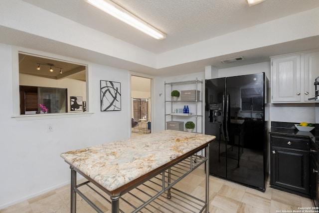 kitchen with a textured ceiling, white cabinetry, and black fridge with ice dispenser