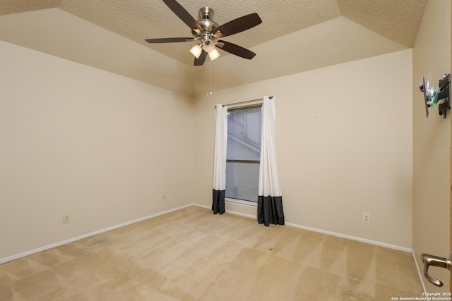 unfurnished room featuring vaulted ceiling, light colored carpet, and a tray ceiling