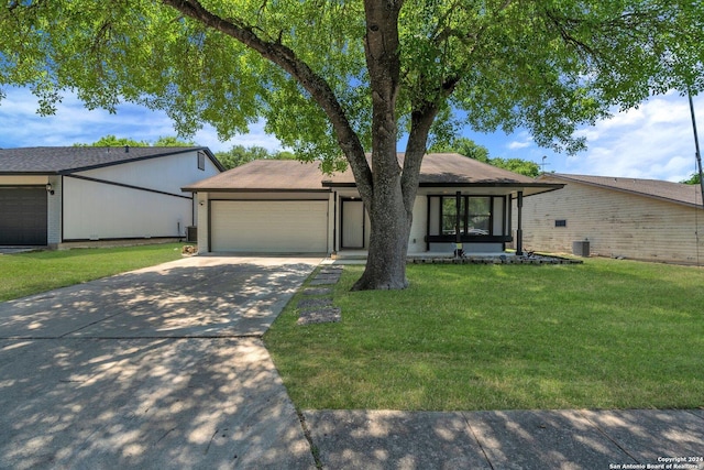 ranch-style home featuring a porch, a garage, cooling unit, and a front yard