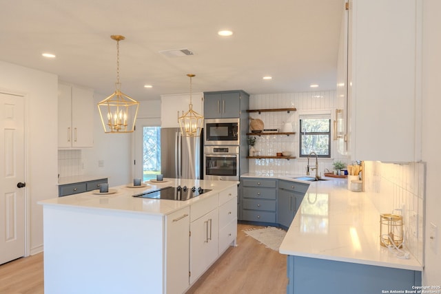 kitchen with sink, a kitchen island, white cabinets, pendant lighting, and stainless steel appliances