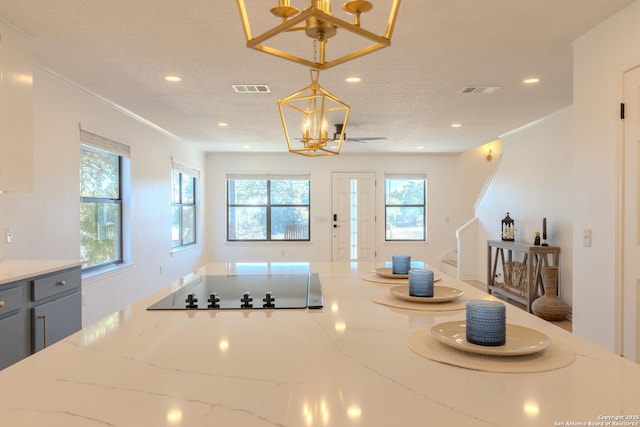 kitchen with pendant lighting, gray cabinetry, light stone countertops, a textured ceiling, and a notable chandelier