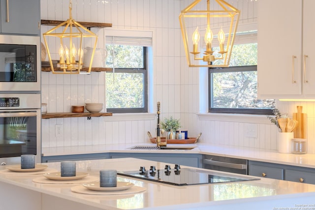 kitchen with a notable chandelier, stainless steel appliances, and pendant lighting