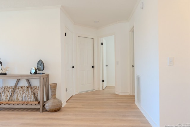 corridor with light hardwood / wood-style flooring and ornamental molding