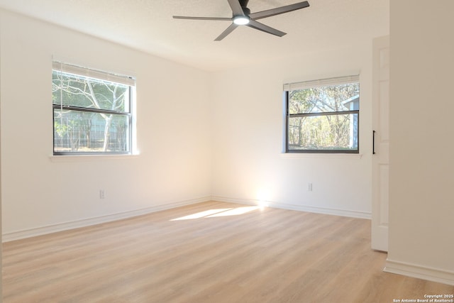 spare room with ceiling fan, plenty of natural light, and light wood-type flooring