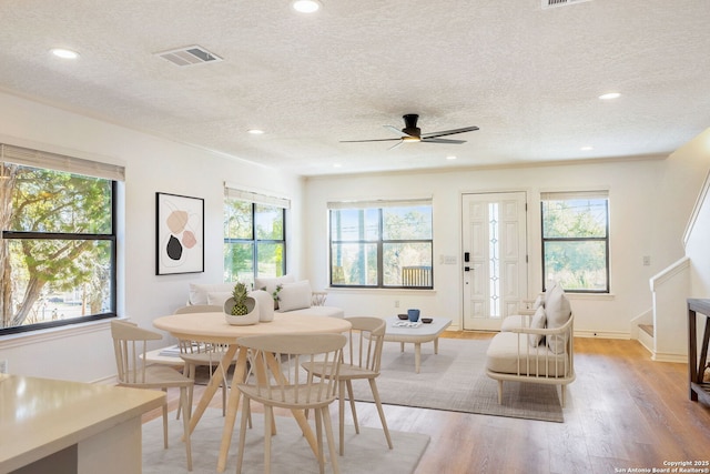 dining area featuring ceiling fan, light hardwood / wood-style floors, a textured ceiling, and a wealth of natural light