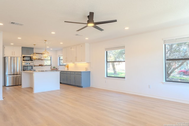 kitchen featuring pendant lighting, gray cabinetry, a center island, and appliances with stainless steel finishes