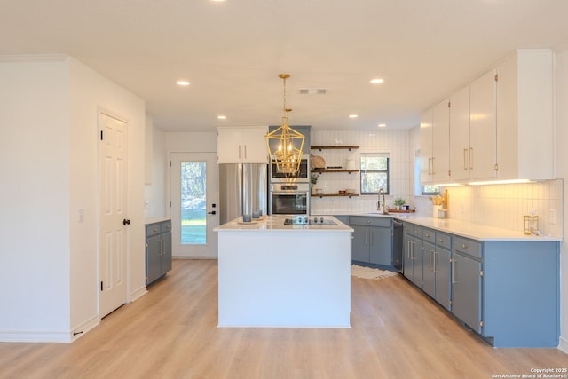 kitchen with stainless steel appliances, a kitchen island, light hardwood / wood-style floors, and decorative light fixtures