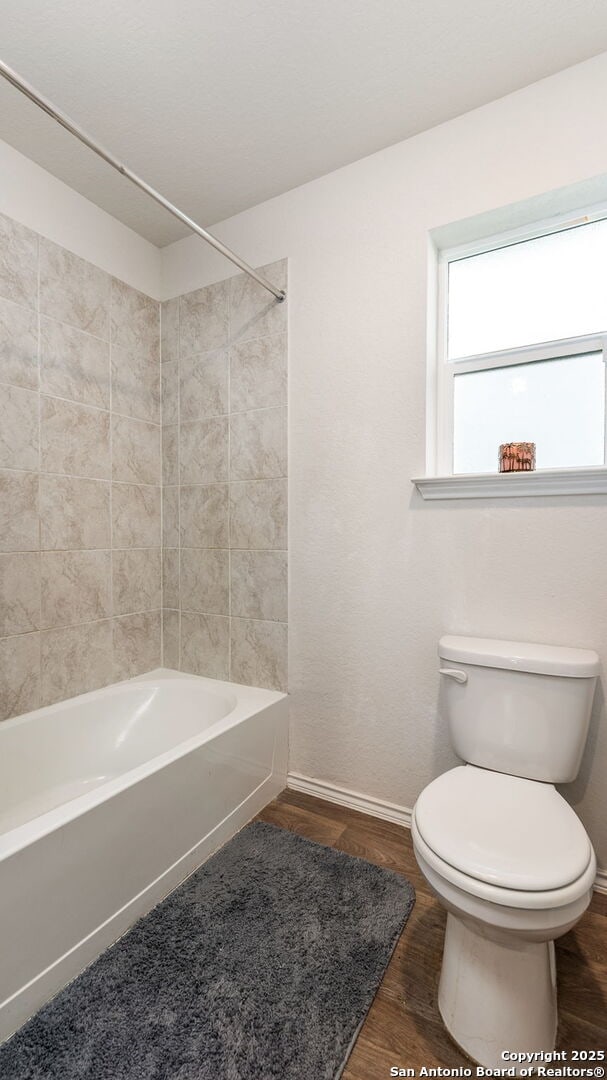 bathroom with toilet, bathtub / shower combination, and hardwood / wood-style floors