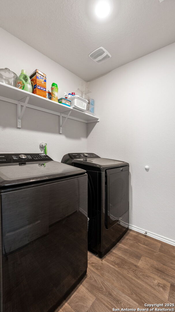 washroom featuring hardwood / wood-style flooring, a textured ceiling, and washing machine and dryer