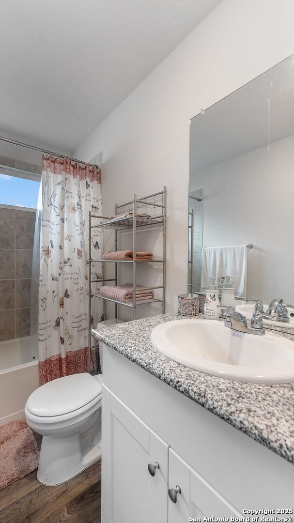 full bathroom with wood-type flooring, toilet, vanity, and shower / tub combo