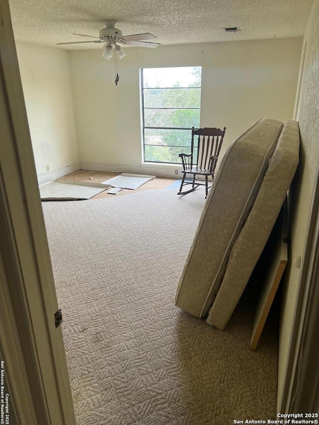 living area with ceiling fan, a textured ceiling, and carpet flooring