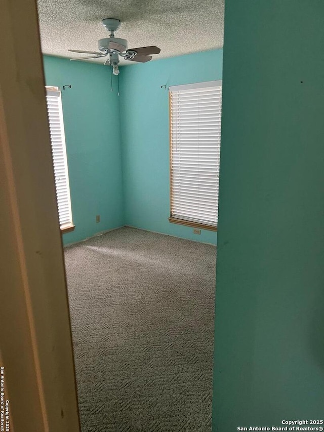 carpeted empty room with a textured ceiling and ceiling fan