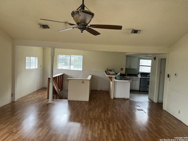 unfurnished living room featuring ceiling fan, a textured ceiling, and dark hardwood / wood-style floors