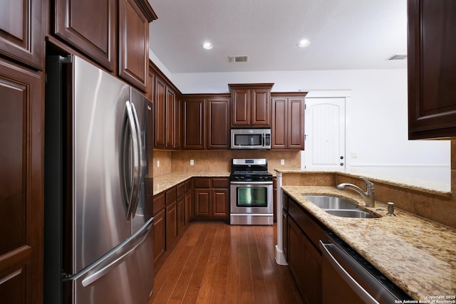 kitchen with sink, dark hardwood / wood-style flooring, decorative backsplash, stainless steel appliances, and light stone countertops