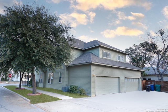 property exterior at dusk with a garage and central AC