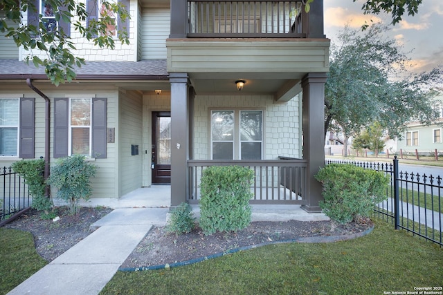 exterior entry at dusk featuring a balcony and covered porch