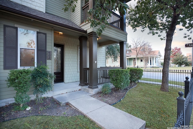 exterior entry at dusk with a balcony, a porch, and a lawn