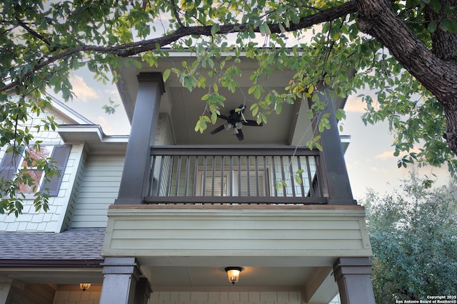 view of side of property featuring a balcony and ceiling fan