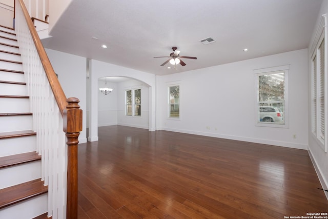 unfurnished living room with dark wood-type flooring and ceiling fan with notable chandelier