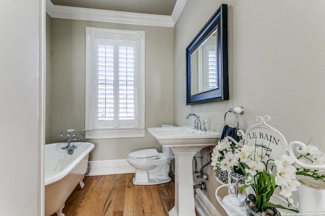 bathroom featuring a washtub, hardwood / wood-style floors, toilet, and crown molding