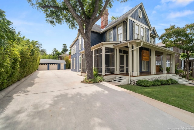 view of home's exterior featuring a porch, a garage, an outbuilding, a sunroom, and a yard