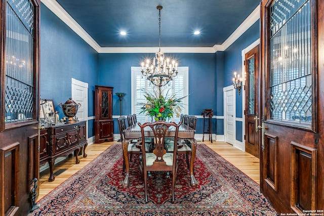 dining space with crown molding, a chandelier, and light hardwood / wood-style flooring