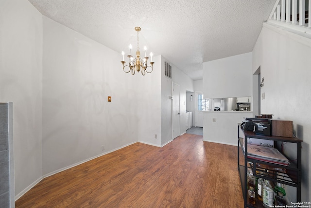 dining room with a textured ceiling, hardwood / wood-style floors, and a chandelier