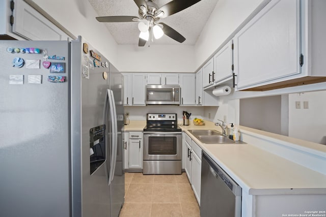 kitchen with a textured ceiling, white cabinetry, stainless steel appliances, sink, and light tile patterned floors