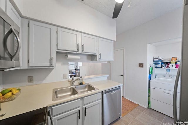 kitchen featuring washer / dryer, stainless steel appliances, sink, ceiling fan, and light tile patterned floors