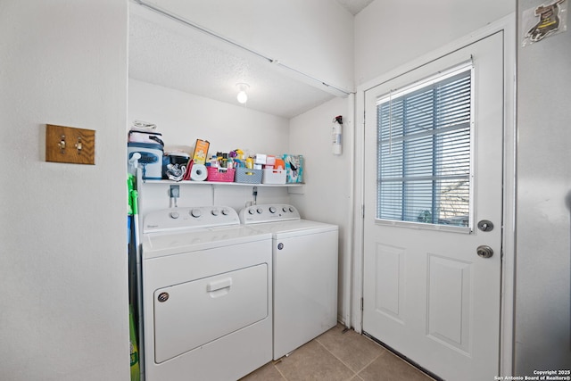 washroom featuring separate washer and dryer, a textured ceiling, and light tile patterned floors