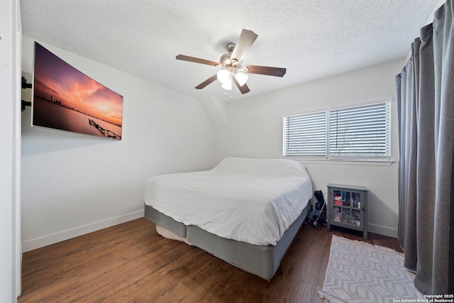 bedroom with ceiling fan, dark wood-type flooring, and a textured ceiling