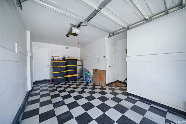 garage with stainless steel fridge and a garage door opener