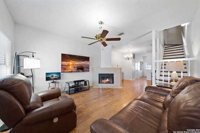 living room with ceiling fan, hardwood / wood-style floors, a textured ceiling, and a fireplace