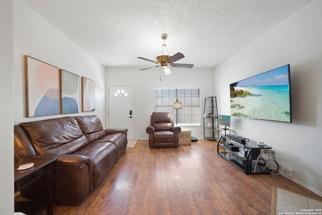 living room with hardwood / wood-style flooring, ceiling fan, and a textured ceiling