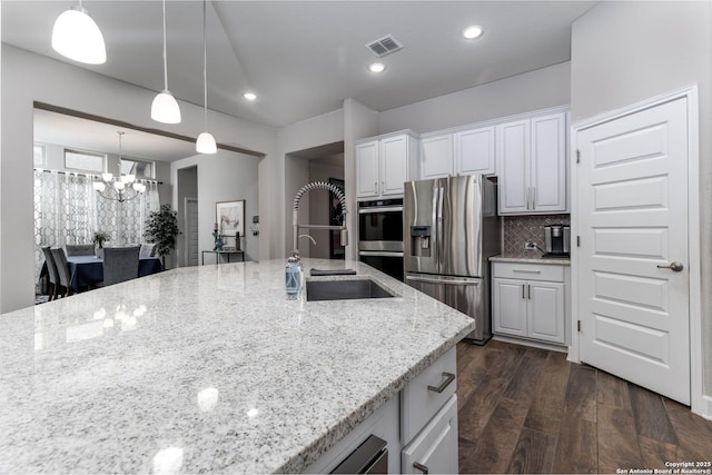 kitchen with light stone counters, white cabinets, backsplash, and appliances with stainless steel finishes